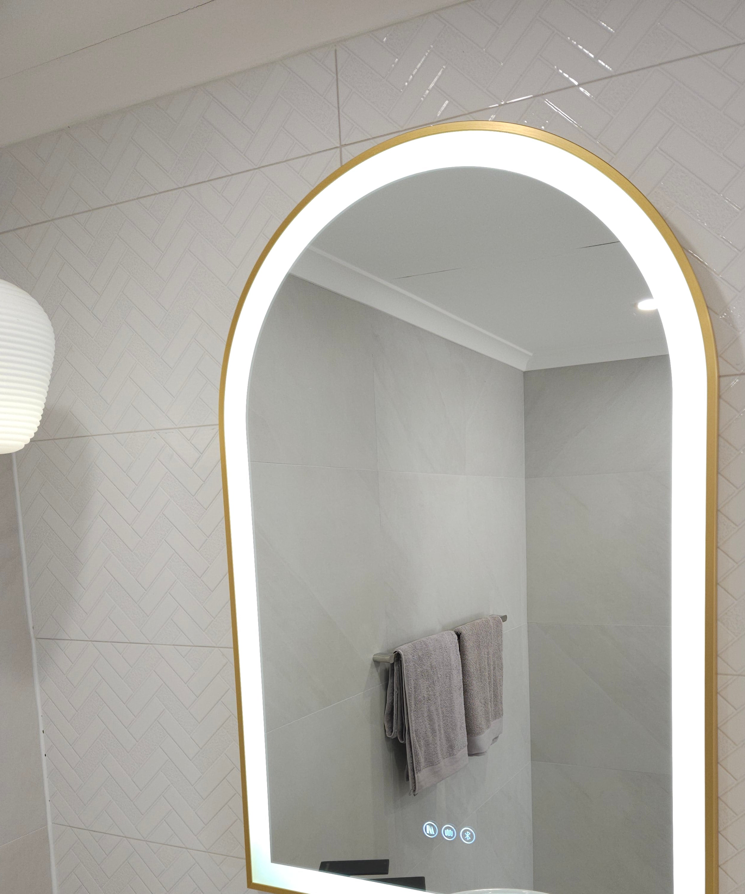 White Tiled Surface with Arch-Shaped Gold-Framed Mirror