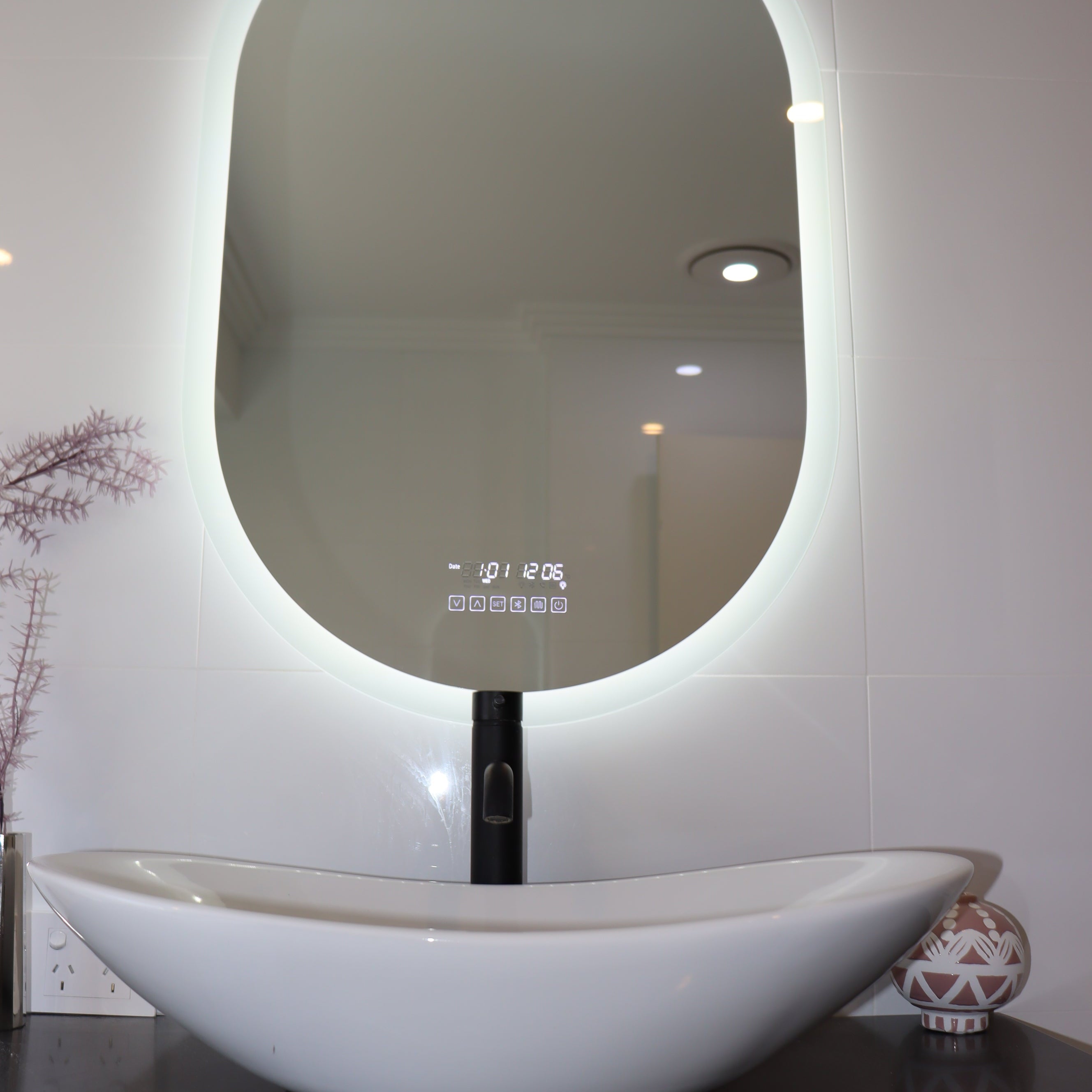 Oval Smart LED mirror emitting intense white backlit LED light, matched with white vessel sink below