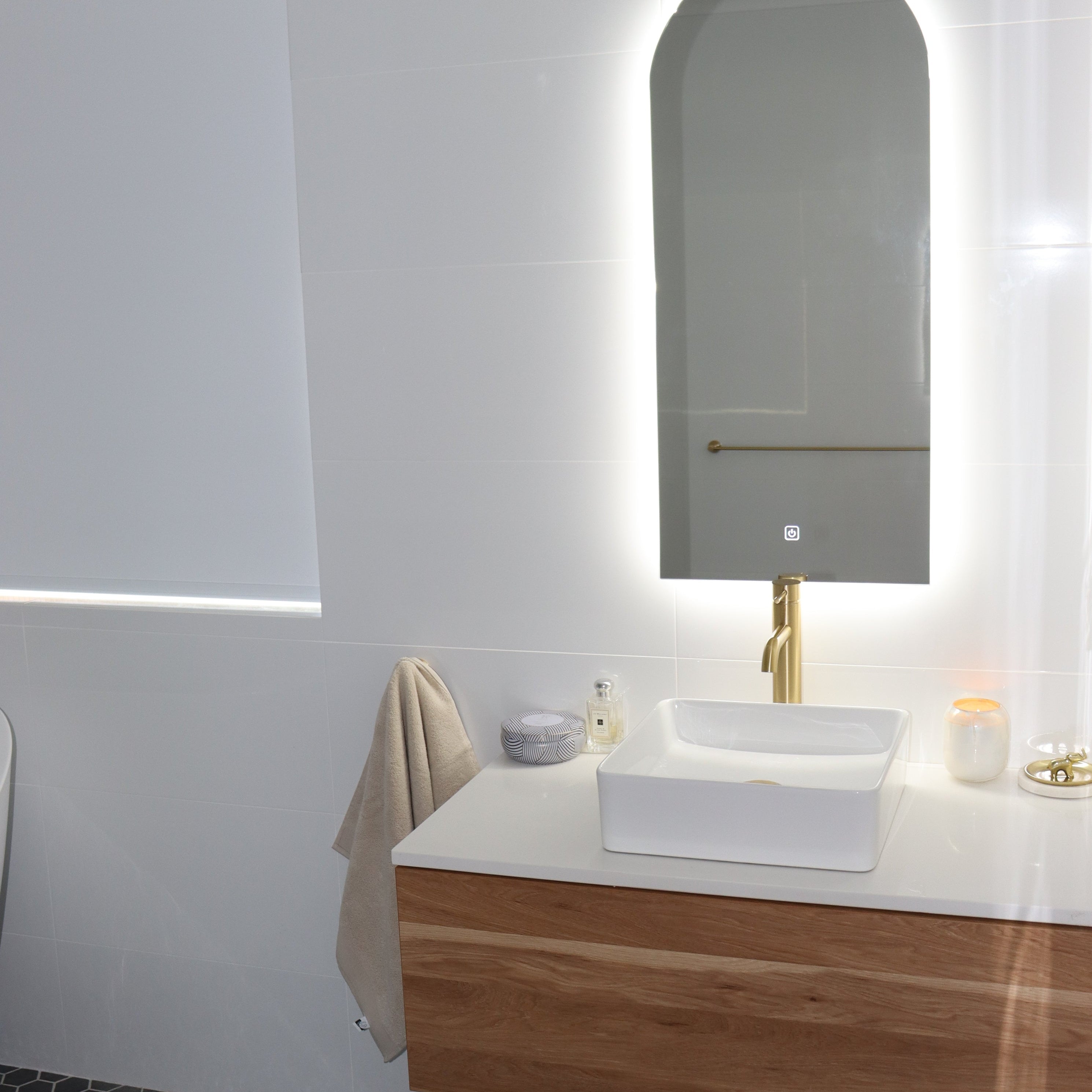 White Bathroom with Backlit LED Mirror, Black Hexagon Floor Tiles, and White-Brown Vanity Cabinet