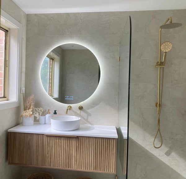 Amalfi Smart LED Mirror Shining in Beige-Tiled Bathroom with Gold Accents, Light Brown Cabinet, White Countertop, and Sink