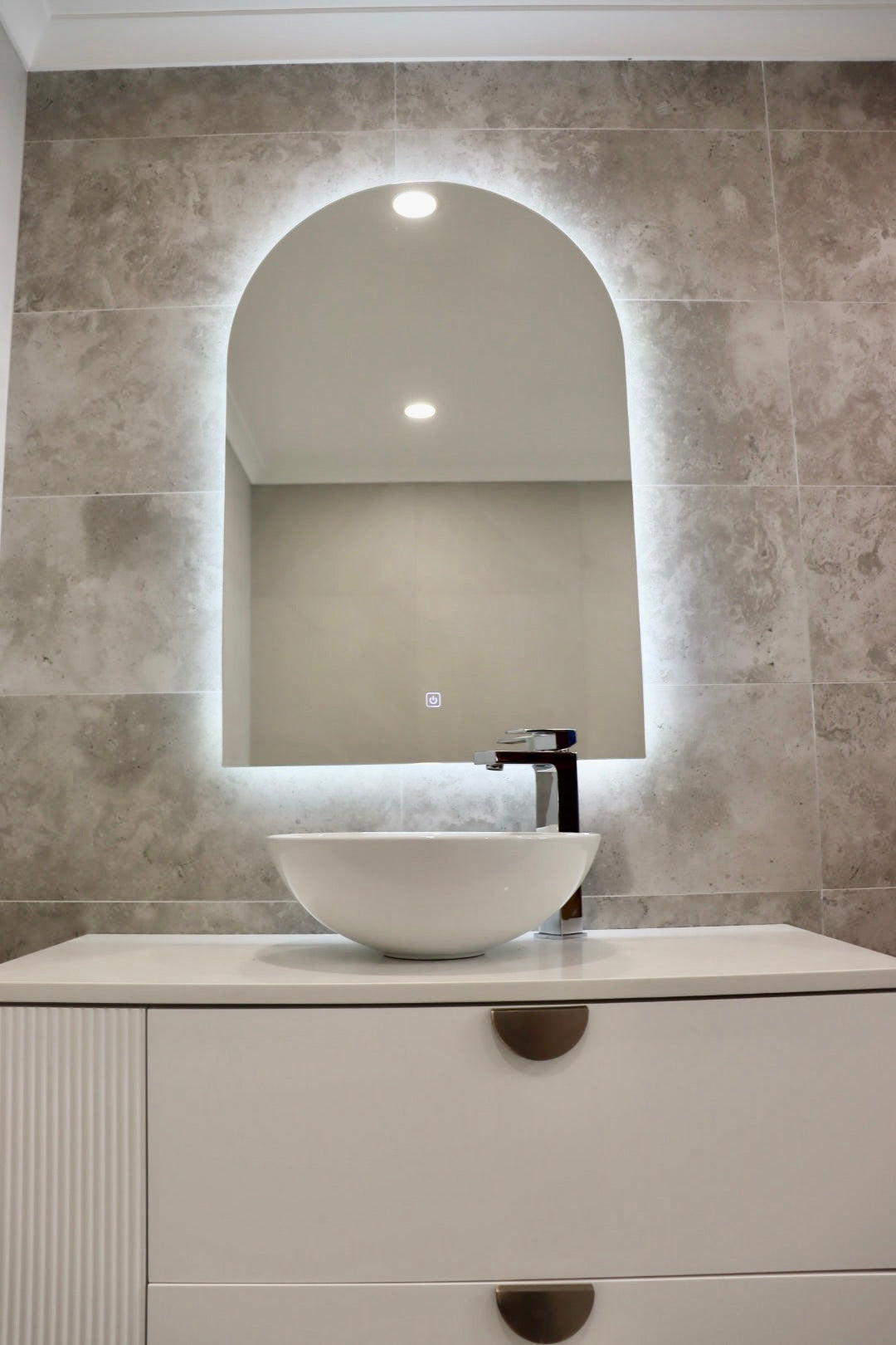Glowing Backlit LED Mirror on Greyish-Brown Wall with Dirty White Vanity Cabinet and Vessel Sink