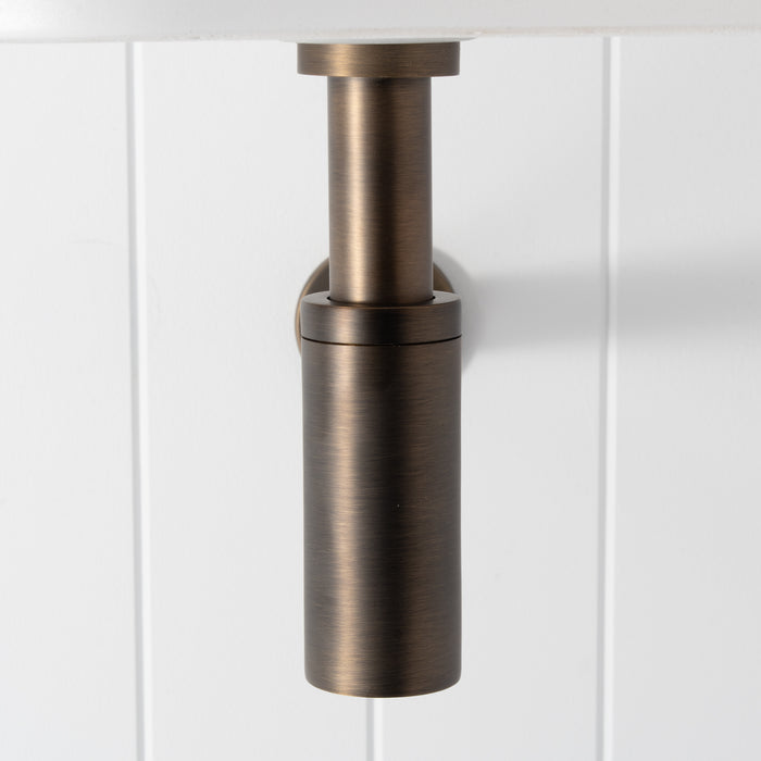 Firenze Basin Bottle Trap in Antique Brass, front view below a white basin on a white vertical-panelled wall