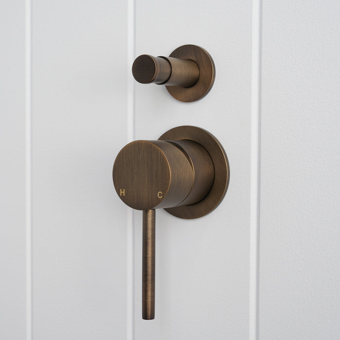 Cannes Shower Diverter and Mixer in Antique Brass, three-quarter view of diverter and lever, white vertical-panelled wall