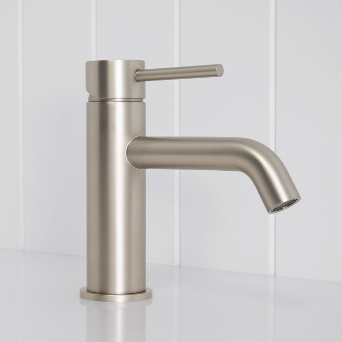 Vienna Short Basin Mixer in Brushed Nickel, side profile of the curved spout and pin lever, white vertical-panelled wall
