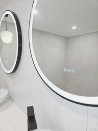 Close-up shot from the right side of two circle Smart LED Mirrors in White bathroom 