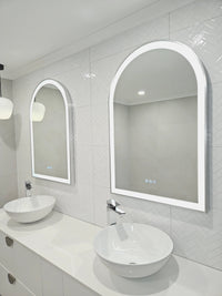 Low Angle Right-Side Perspective of Two Arch-Shaped Smart LED Mirrors in all-white bathroom