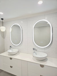 Doorway glimpse of white bathroom's elegant vanity mirrors and cabinets