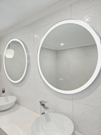 Side View of Two Silver Frame Circle Smart LED Mirrors in White-on-White Bathroom