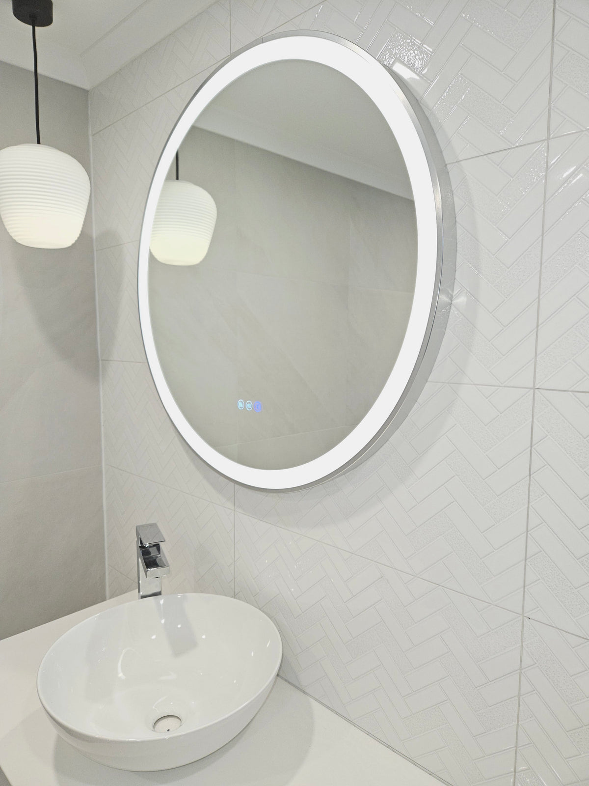 Low angle shot: Silver frame Smart Circle LED Mirror in white bathroom with pendant light and sink