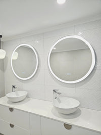 Two silver frame Smart Circle LED Mirrors on white bathroom with a pendant light and two white sink