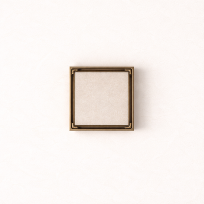 Granada Tile Insert Floor Waste in Antique Brass, top-down view, light stone tile in the cover on a plain white background