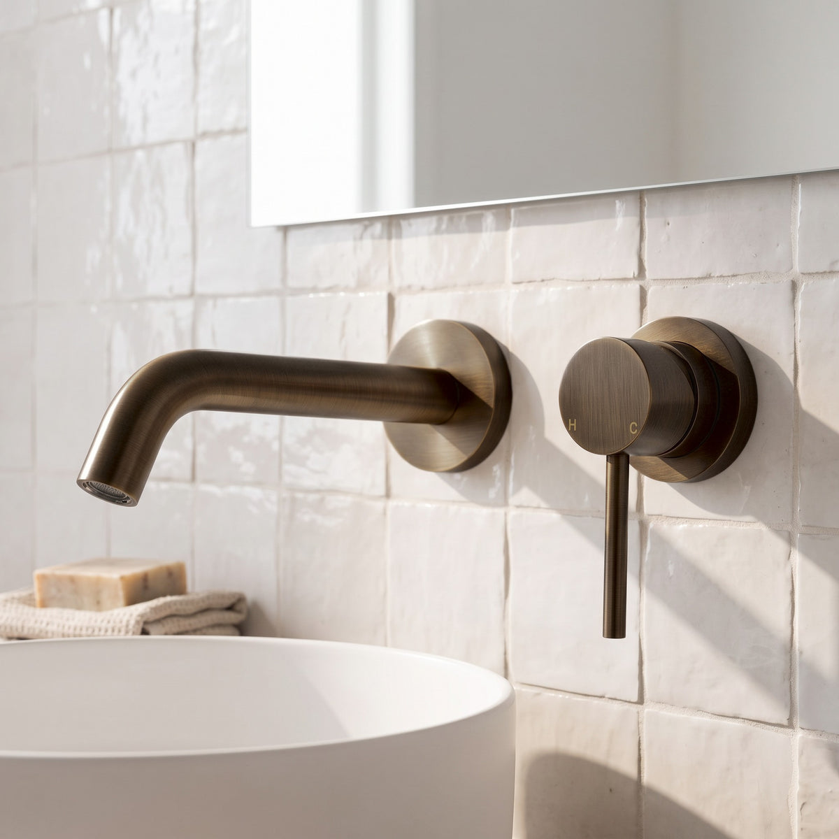 Milano Wall Spout Plus Wall Mixer in Antique Brass, close-up on white handmade tiles above a white basin