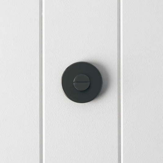 Prague Door Lock in Brushed Gunmetal, front view of the slotted emergency release on a white vertical-panelled wall