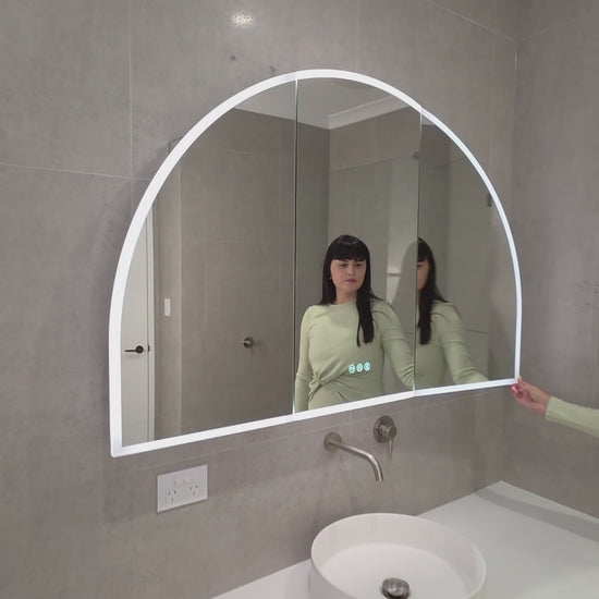 Female opening the door of an LED arched mirror cabinet and touching the display buttons
