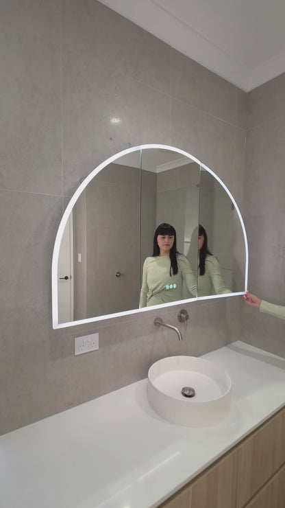 Female opening the door of an LED arched mirror cabinet and touching the display buttons