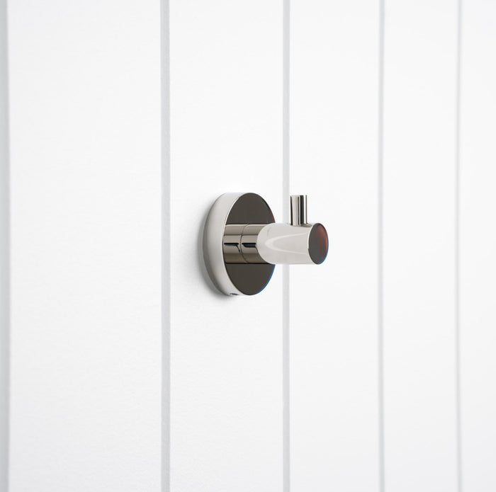 Copenhagen Robe Hook in Chrome, three-quarter view on a white vertical-panelled wall