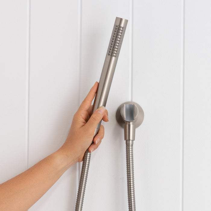 Versailles Handheld Shower Head with Hose in Brushed Nickel, hand holding the slim handpiece beside the round wall bracket
