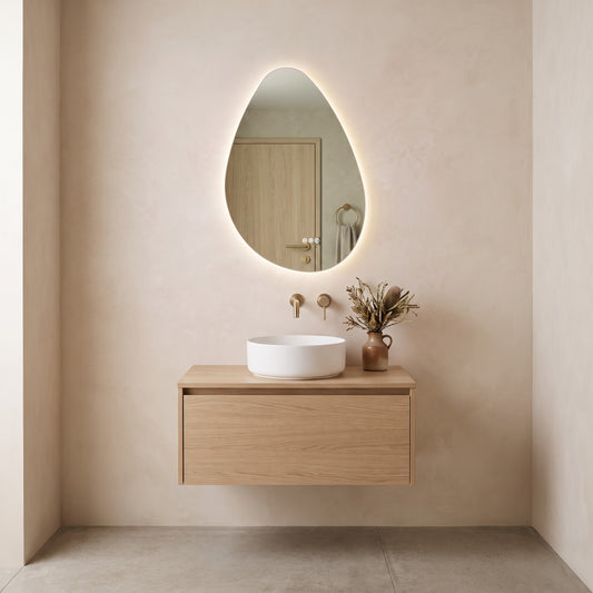 The Sorrento frameless backlit LED mirror hung portrait above an oak vanity, white basin and brushed brass wall tap
