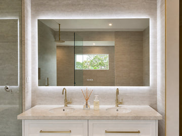 The Venice backlit LED bathroom mirror above a white double vanity with brass tapware and stone benchtop