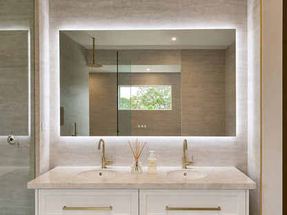 The Venice backlit LED bathroom mirror above a white double vanity with brass tapware and stone benchtop
