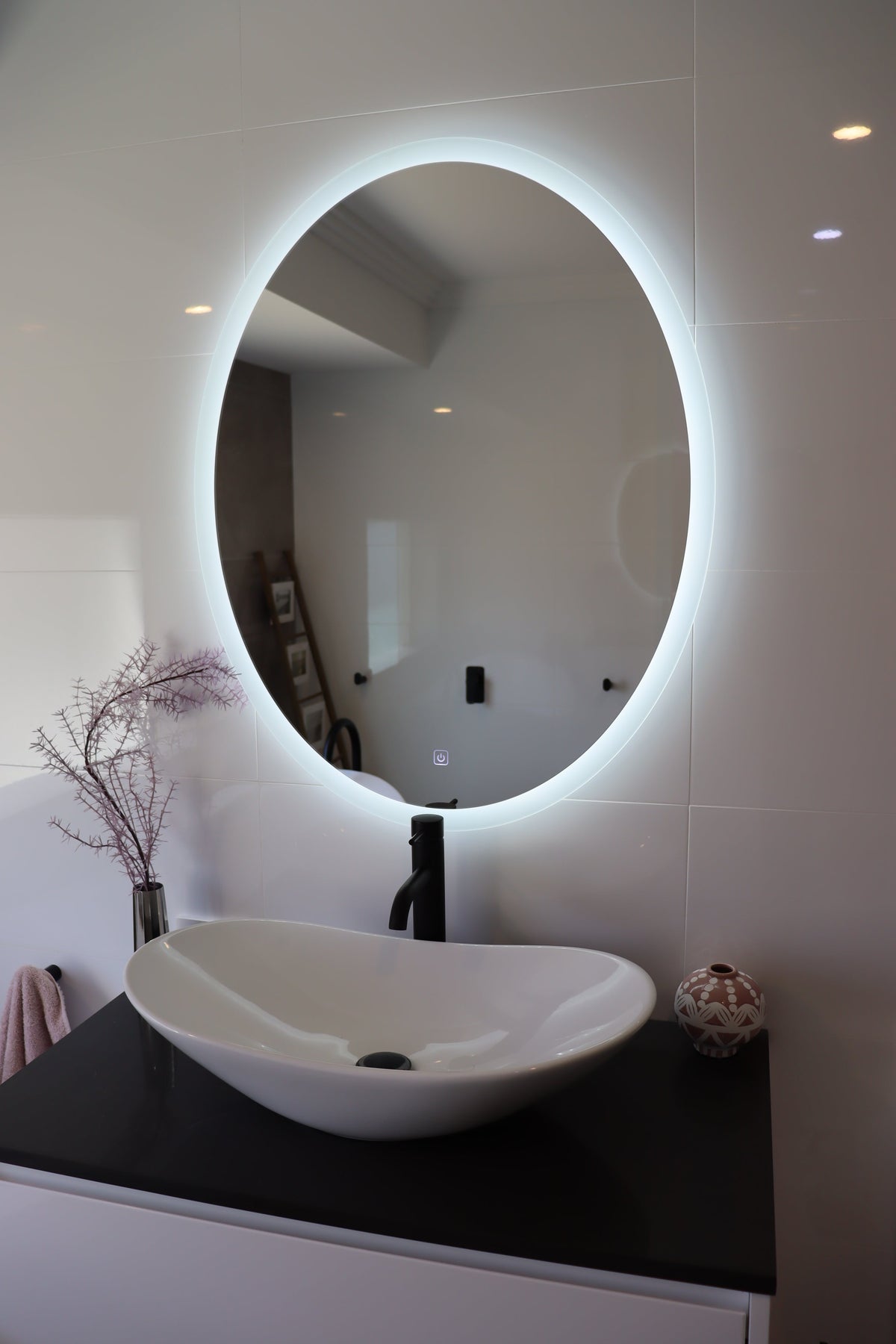 Soft Glow of Backlit Oval LED Mirror Casting Gentle Radiance in White Glossy Bathroom
