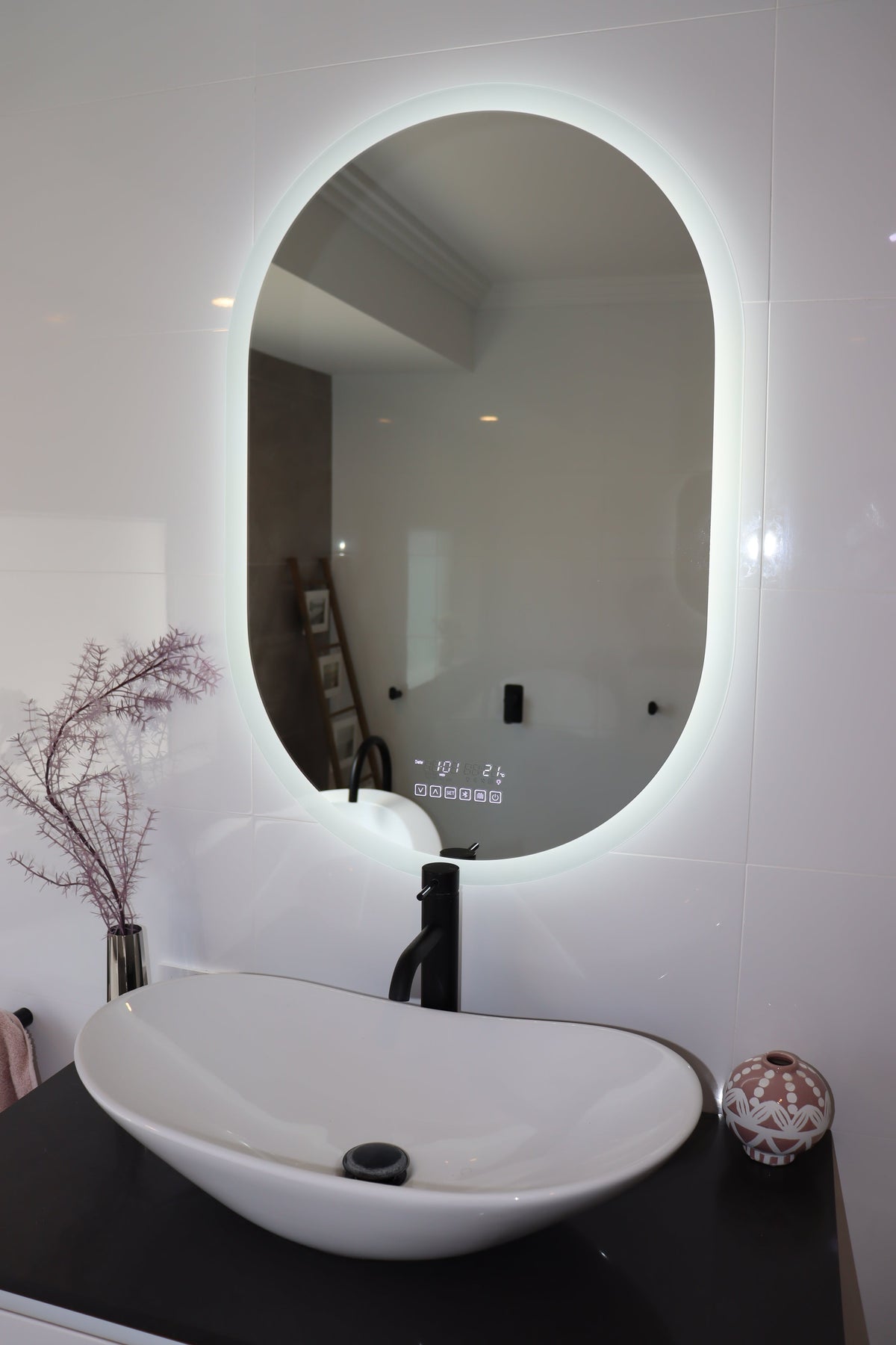 Oval Smart LED mirror with brilliant white backlit LED light and black bathroom countertop