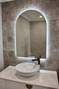 Illuminated Arch-Shaped LED Mirror on Greyish Brown Wall with White Sink and Cabinet