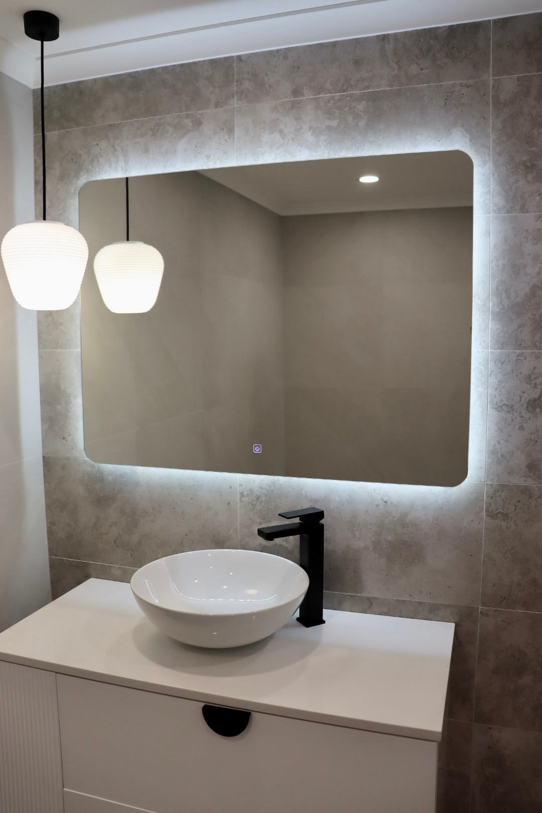 Right side angled view of a Well-lit vanity area from the Backlit LED mirror and pendant light