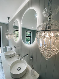 Elegant bathroom from smart LED mirrors, chandelier-like pendant lights, white scheme, grey walls