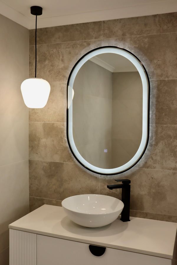 Peaceful Bathroom with Oval LED Mirror in White Light and Pendant Light Casting a Subtle Yellow Glow